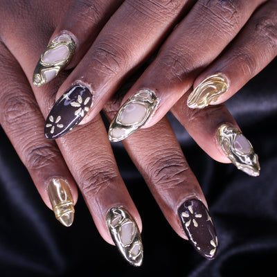 Close-up of a hand with ornate nail designs on a black background